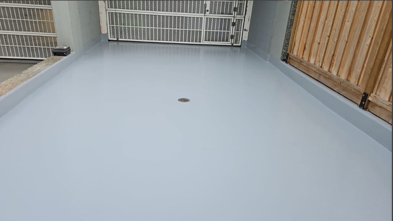 The finished entrance deck under a continuous grey membrane, sealed to the drain and up every edge